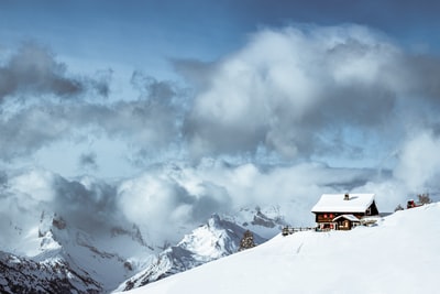 白昼白云下雪山上的棕色房子